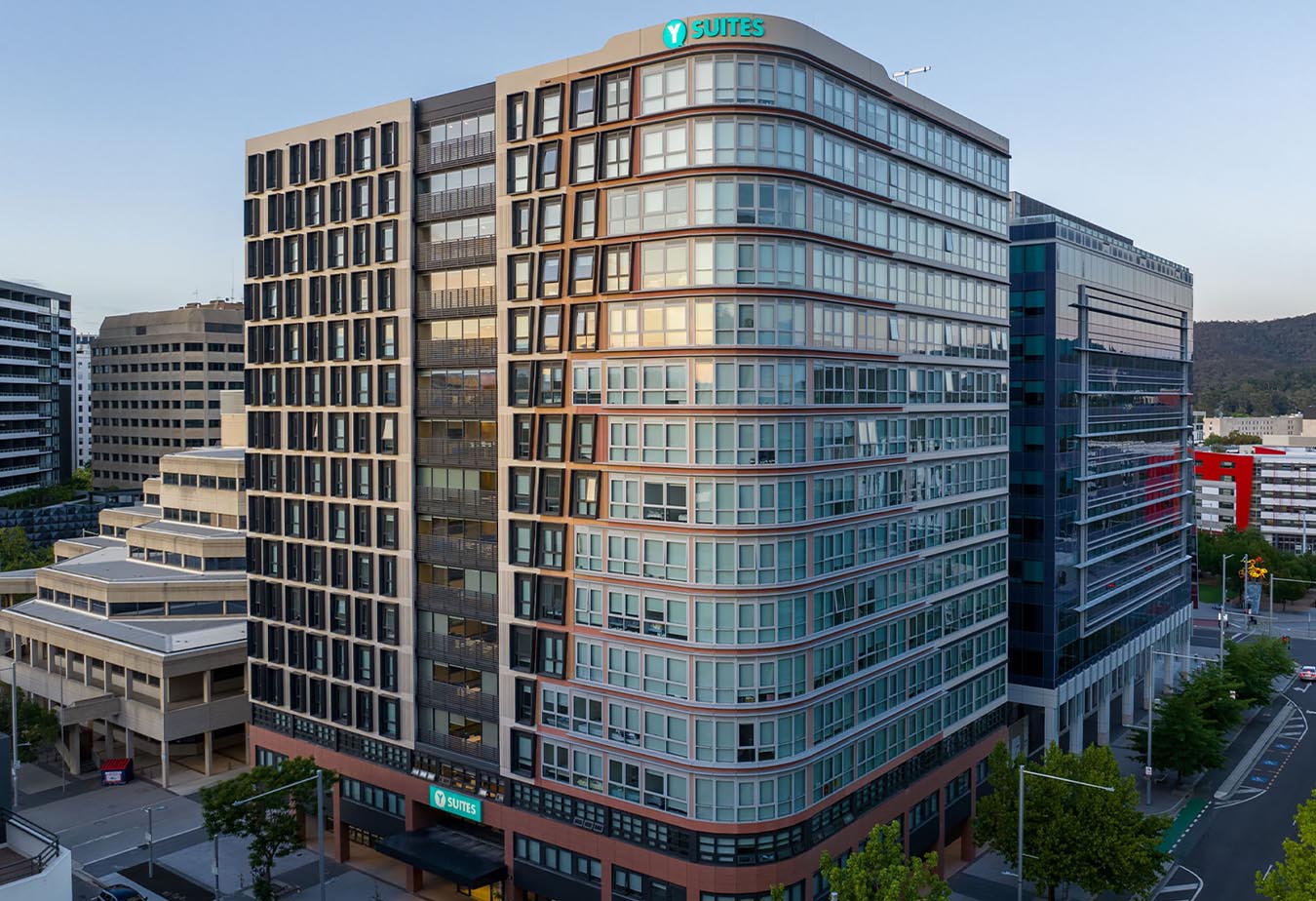 A tall multi-story building, surrounded by office and residential buildings, streets, and patches of greenery.