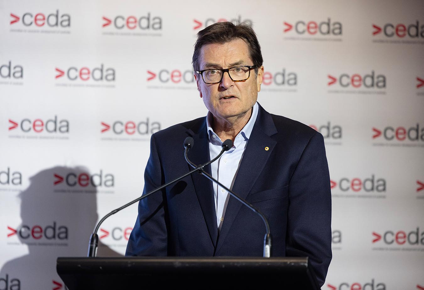 Greg Combet speaking behind a podium with a microphone, in front of a CEDA-branded backdrop.