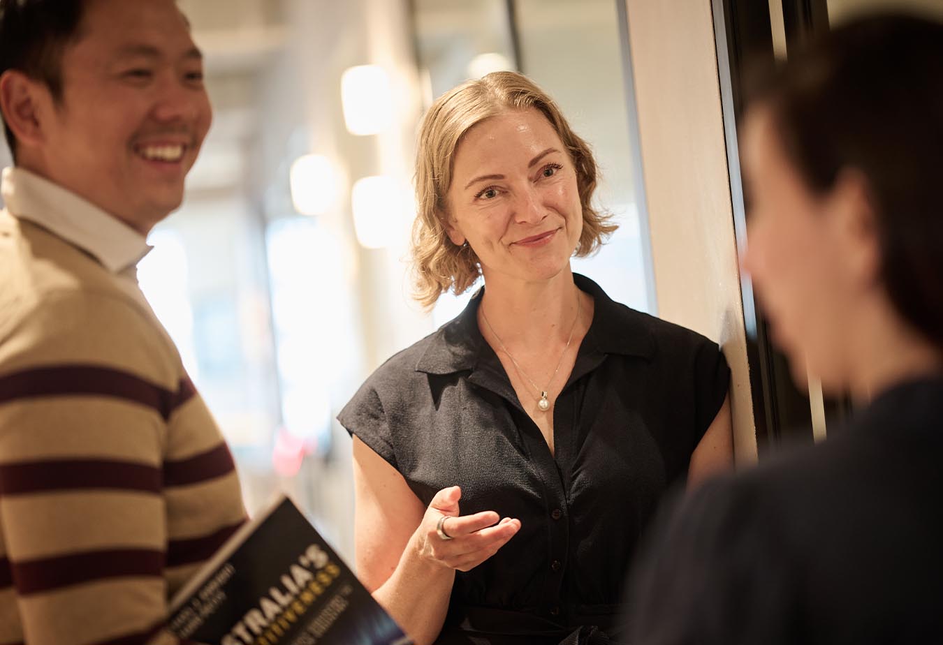 Gillian Denison smiling at a colleague in an indoors office setting.