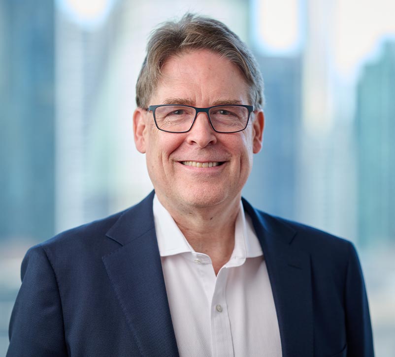 A professional portrait of Mr James Craig with a blurred city background.